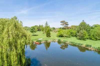 a view of a lake with a boat on it at Charming cottage in beautiful countryside with a boating lake - The Calf Pens in Ipswich
