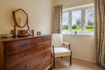 a dresser with a mirror and a chair next to a window at Charming cottage in beautiful countryside with a boating lake - The Calf Pens in Ipswich