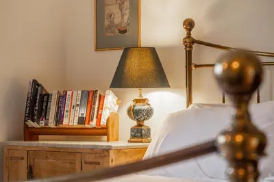 a bed with a lamp on a table with books at Charming cottage in beautiful countryside with a boating lake - The Calf Pens in Ipswich