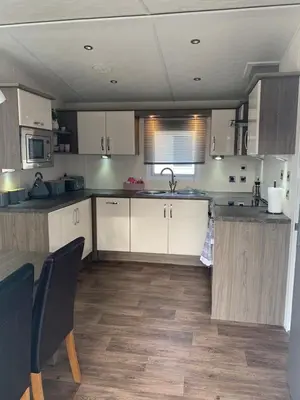 a kitchen with white cabinets and a wooden floor at DaisyChain Getaways The perfect place to Stay Play and Getaway in East Mersea