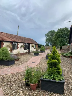 a garden with trees and plants in front of a house at Bluebell Barn in Banham