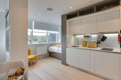 a kitchen with white cabinets and a bed in a room at Kings Road Apartments in Brentwood