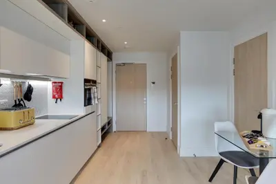 a kitchen with white cabinets and a table and a chair at Kings Road Apartments in Brentwood