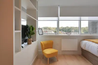 a bedroom with a bed and a chair and a window at Kings Road Apartments in Brentwood