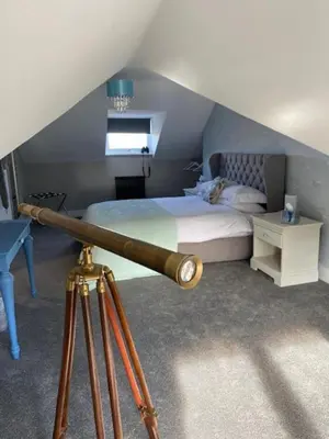 a room with a bed and a telescope at Seaview B&B in Harwich