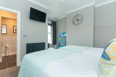 a bedroom with a white bed and a clock on the wall at Seaview B&B in Harwich