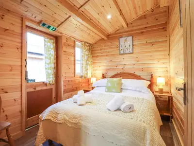 a bedroom with a bed in a log cabin at Buttercup Lodge in Leiston