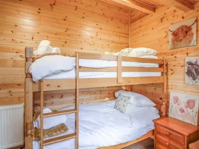 a bedroom with two bunk beds in a log cabin at Buttercup Lodge in Leiston