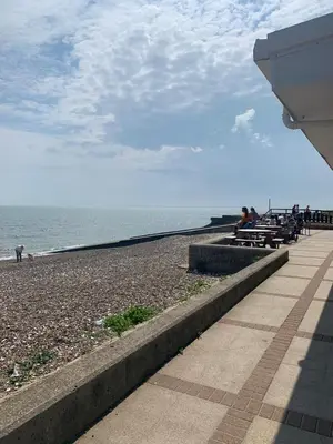 a beach with people sitting on benches near the water at DaisyChain 2 Getaways - The perfect place to Stay - Play - Getaway in East Mersea