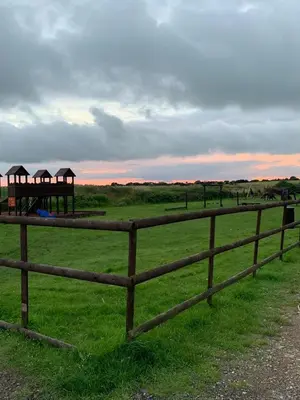 a wooden fence in a field with a gazebo at DaisyChain 2 Getaways - The perfect place to Stay - Play - Getaway in East Mersea