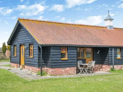 a black house with two chairs in front of it at Orchard Cottage in Saint Osyth