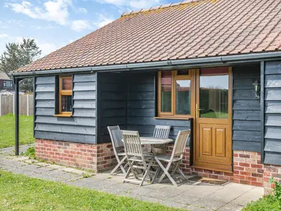 a small blue house with a table and chairs at Orchard Cottage in Saint Osyth