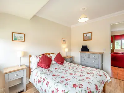 a bedroom with a bed with red pillows on it at Orchard Cottage in Saint Osyth