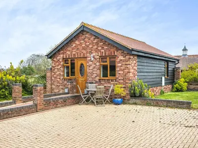 a brick house with a table and chairs in front of it at Dairy Cottage in Saint Osyth