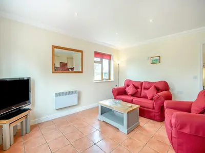 a living room with two red couches and a tv at Dairy Cottage in Saint Osyth