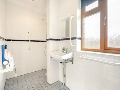 a white bathroom with a sink and a window at Dairy Cottage in Saint Osyth