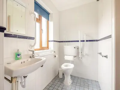 a white bathroom with a sink and a toilet at Dairy Cottage in Saint Osyth