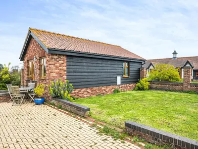 a brick house with a yard in front of it at Dairy Cottage in Saint Osyth