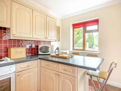 a kitchen with wooden cabinets and a black counter top at Dairy Cottage in Saint Osyth