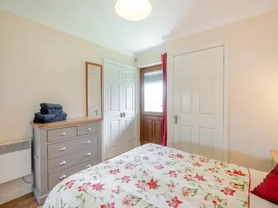 a white bedroom with a bed and a dresser at Peartree Cottage in Saint Osyth