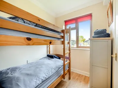 a bedroom with two bunk beds and a window at Peartree Cottage in Saint Osyth