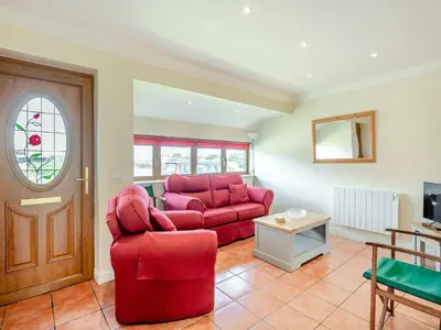 a living room with a red couch and a table at Peartree Cottage in Saint Osyth