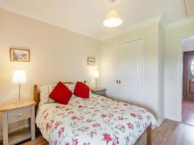 a bedroom with a bed with red pillows on it at Peartree Cottage in Saint Osyth