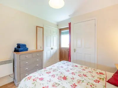 a bedroom with a bed and a dresser at Willowtree Cottage in Saint Osyth