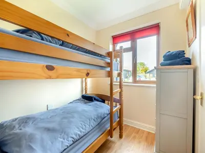 a bedroom with two bunk beds and a window at Willowtree Cottage in Saint Osyth