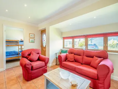 a living room with two red couches and a table at Willowtree Cottage in Saint Osyth