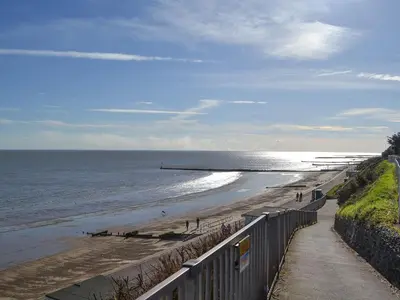 a view of a beach with a fence and the ocean at Willowtree Cottage in Saint Osyth