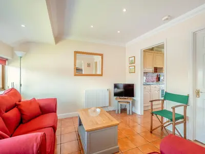 a living room with a red couch and a table at Willowtree Cottage in Saint Osyth