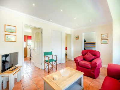 a living room with a red chair and a table at Willowtree Cottage in Saint Osyth