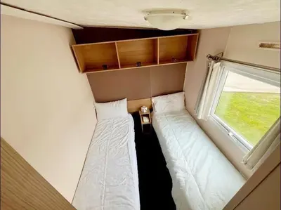 two beds in a small room with a window at La Casa Greenaway in Jaywick Sands