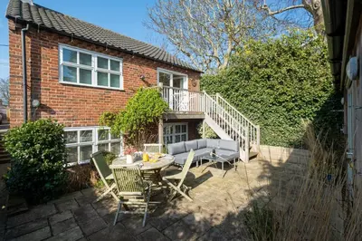 a patio with a table and chairs in front of a house at Drake House in Aldeburgh