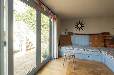 a bedroom with a bed and a stool in front of a window at Drake House in Aldeburgh
