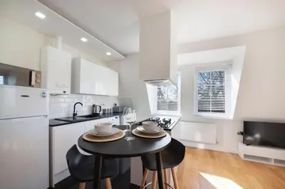 a kitchen with a table with two chairs and a refrigerator at Spacious One Bed loft Apartment in Birchanger