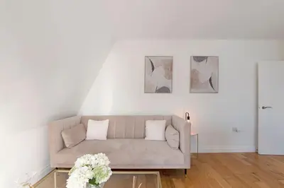 a living room with a couch and flowers on a table at Spacious One Bed loft Apartment in Birchanger