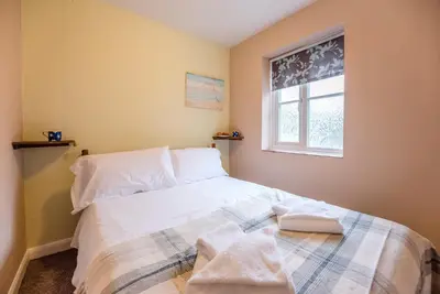 a bedroom with a bed with white sheets and a window at The Woodshed, Benhall in Saxmundham