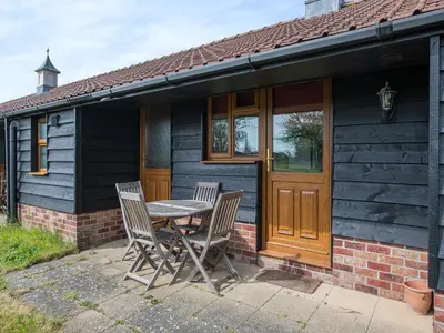 a table and chairs in front of a house at Meadowview Cottage in Saint Osyth