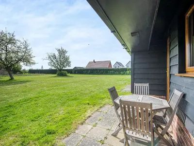 a table and chairs on the porch of a house at Meadowview Cottage in Saint Osyth