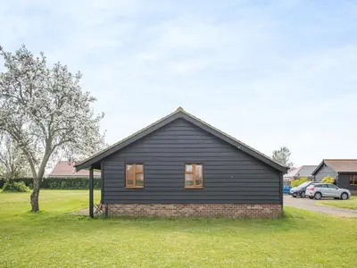 a black house in a yard with a tree at Meadowview Cottage in Saint Osyth