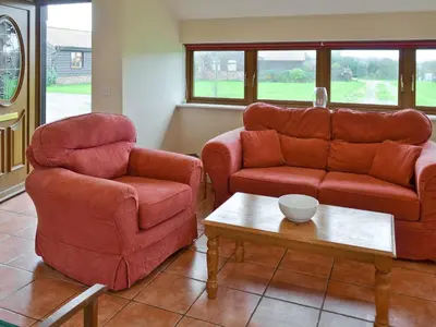 a living room with two chairs and a couch and a table at Meadowview Cottage in Saint Osyth