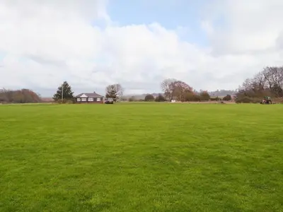 a large green field with a house in the distance at Meadowview Cottage in Saint Osyth