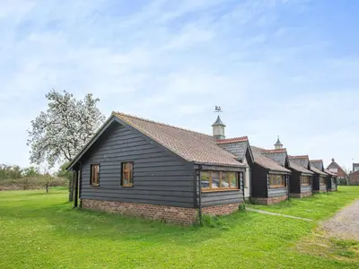 a row of houses in a field with a church at Meadowview Cottage in Saint Osyth