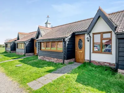 a row of cottages in front of a church at Appletree Cottage in Saint Osyth