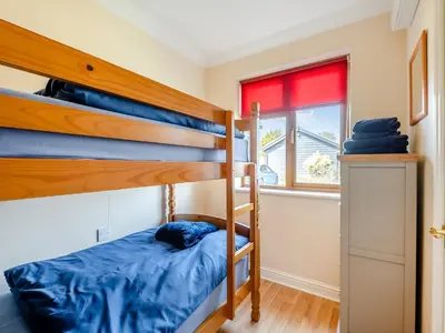 a bedroom with two bunk beds and a window at Appletree Cottage in Saint Osyth