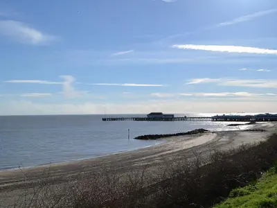 a beach with a pier in the water at Appletree Cottage in Saint Osyth