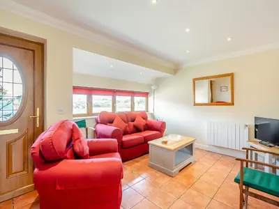a living room with two red couches and a tv at Appletree Cottage in Saint Osyth