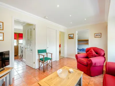 a living room with a red couch and a table at Appletree Cottage in Saint Osyth